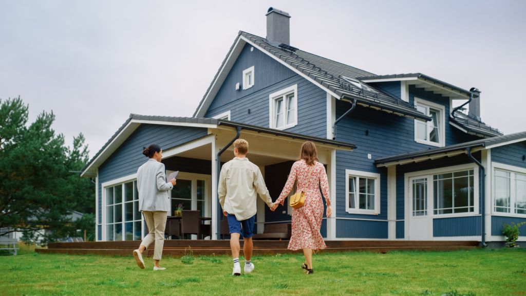 Couple approaching blue house with real estate agent