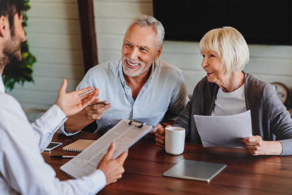 A man conversing with an elderly couple about estate planning, retirement planning or aged care at a table.