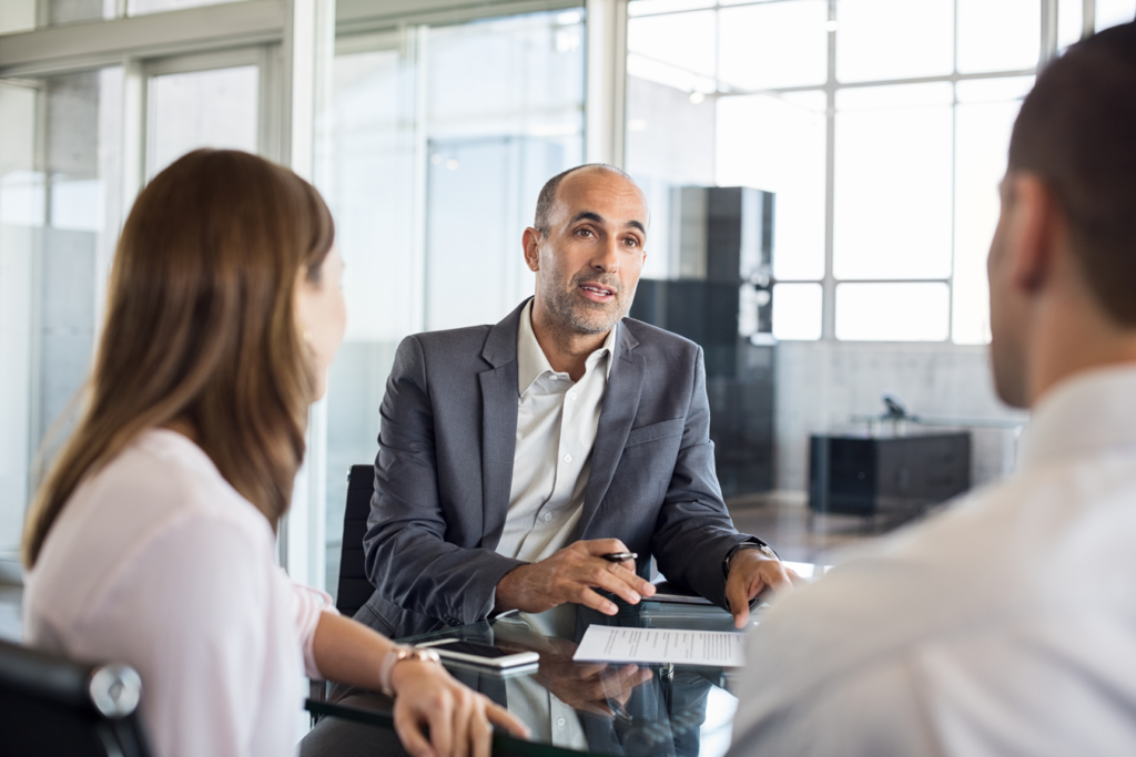 A man in a business suit engages in conversation with two women in a professional setting.