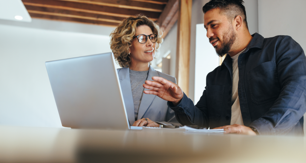 Man and woman discussing risks while looking at computer in modern office space