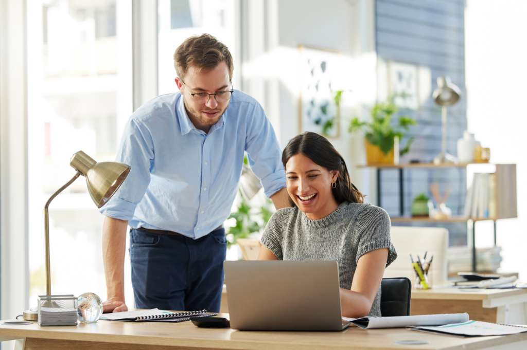 A man and woman collaborating on a laptop computer.