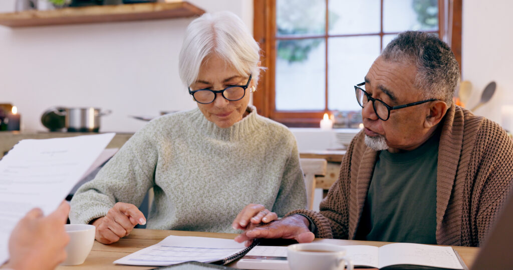 old couple, paperwork and reading for inheritance will in retirement, planning and bills or documents. Senior people, marriage and communication or discussion for future, saving and finance in kitchen at home