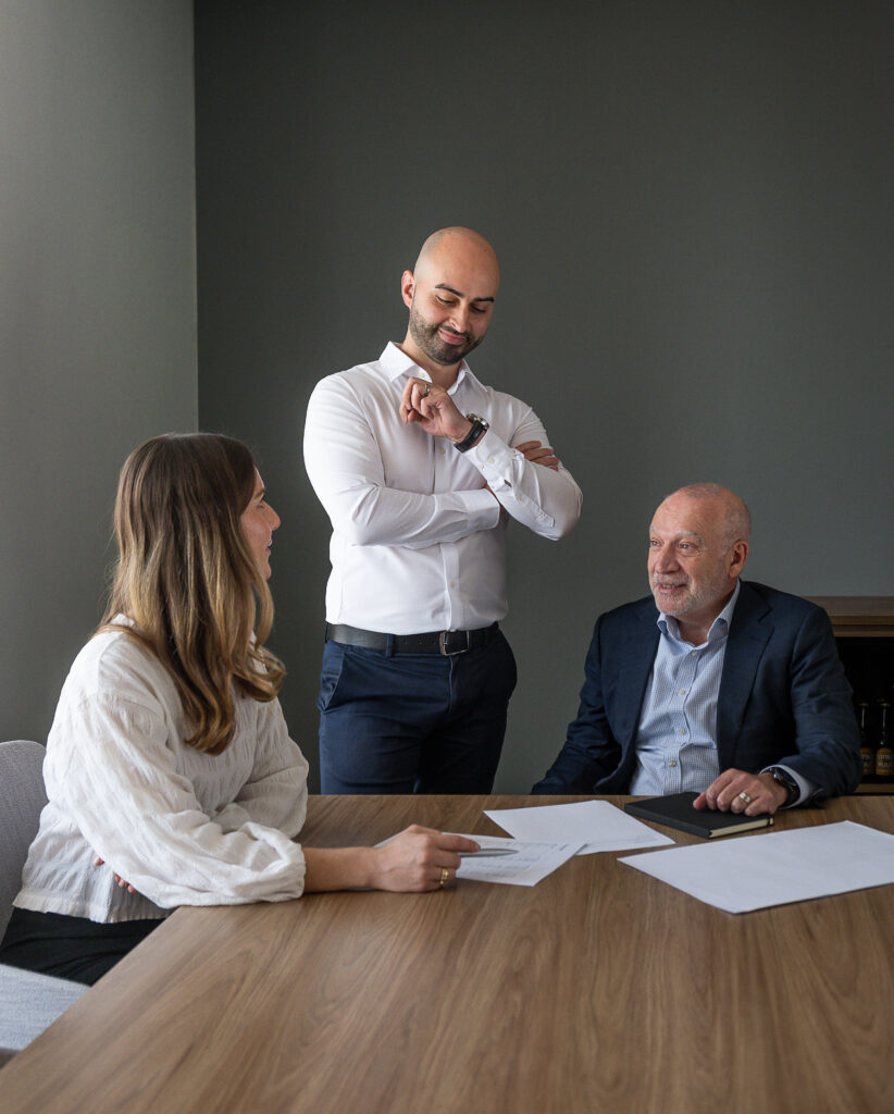 three advisors in a room having a meeting with papers on the table